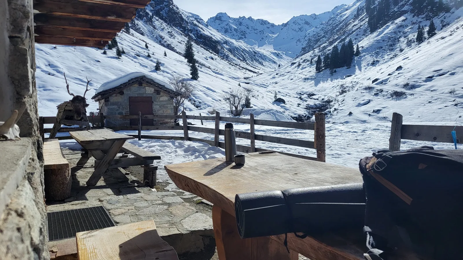 Tisch und Bank vor der Alphütte mit Blick in das verschneite Hochtal